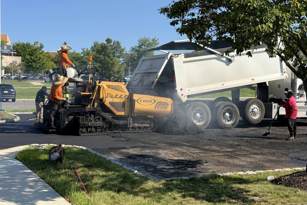 Inscripción de choferes: vagoneta descargando mezcla en la tolva de la pavimentadora